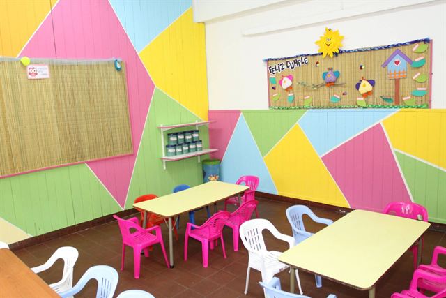 Sala amarilla, con paredes de colores y sillas infantiles