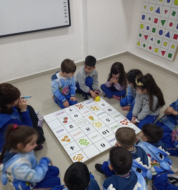 Los chicos programan el recorrido de un robot sobre un tablero con números y frutas