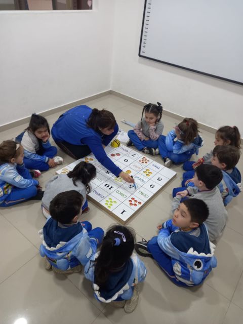 Una docente señala el tablero mientras los chicos miran el recorrido del robot