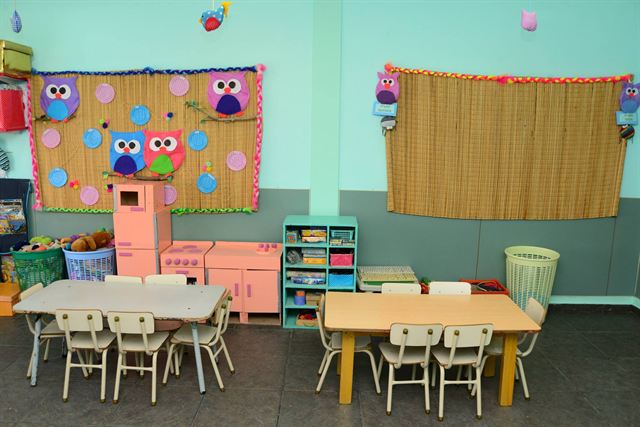 Sala verde, con rincón de juego y mesas para trabajar en grupo